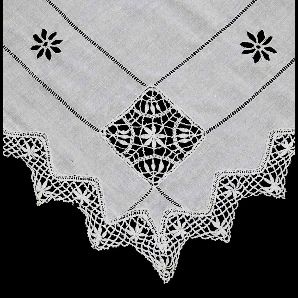 Detail of lace-trimmed corner with intricate openwork on centenary Portuguese linen tablecloth.
