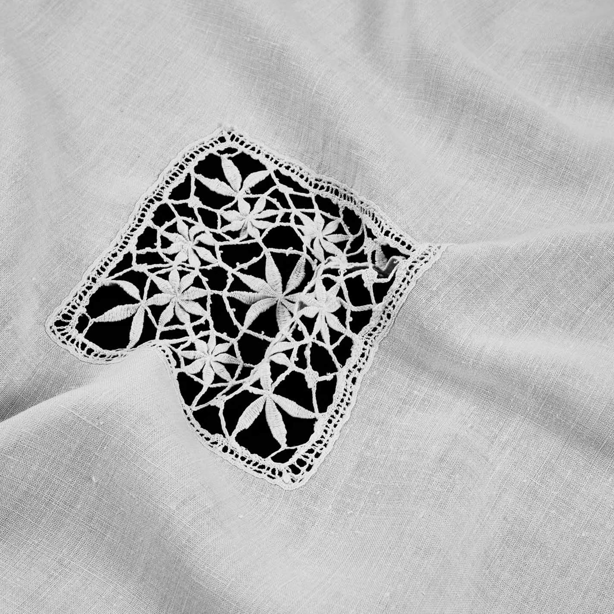 Detail of lace-trimmed corner with intricate openwork on centenary Portuguese linen tablecloth.