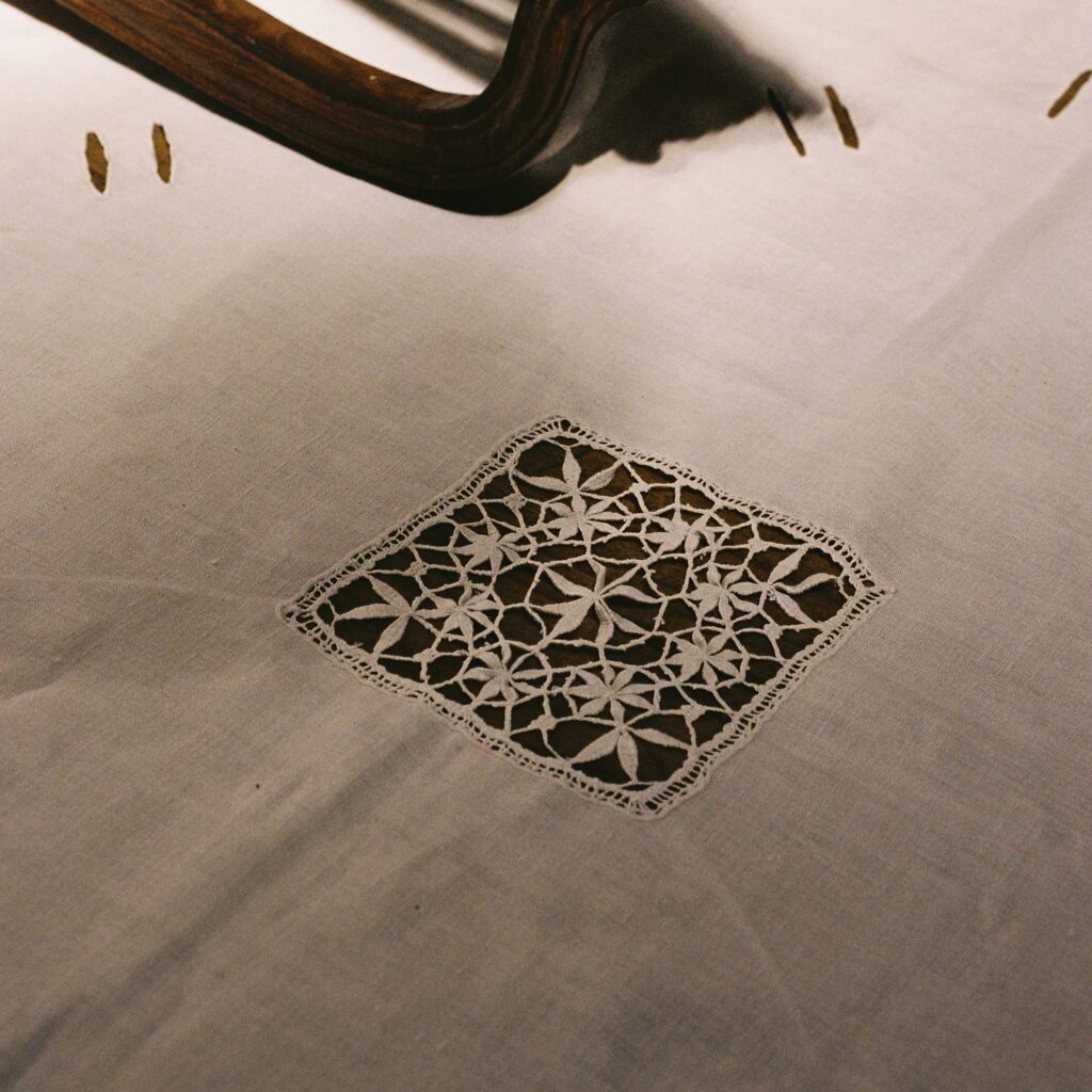 Portuguese lace and linen tablecloth photographed in warm interior light showing handmade craftsmanship.