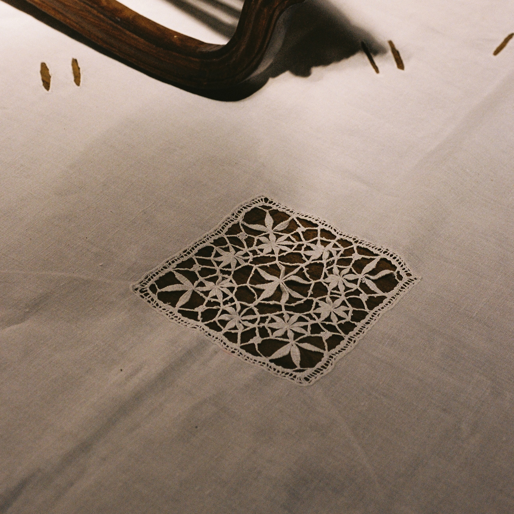 Portuguese lace and linen tablecloth photographed in warm interior light showing handmade craftsmanship.