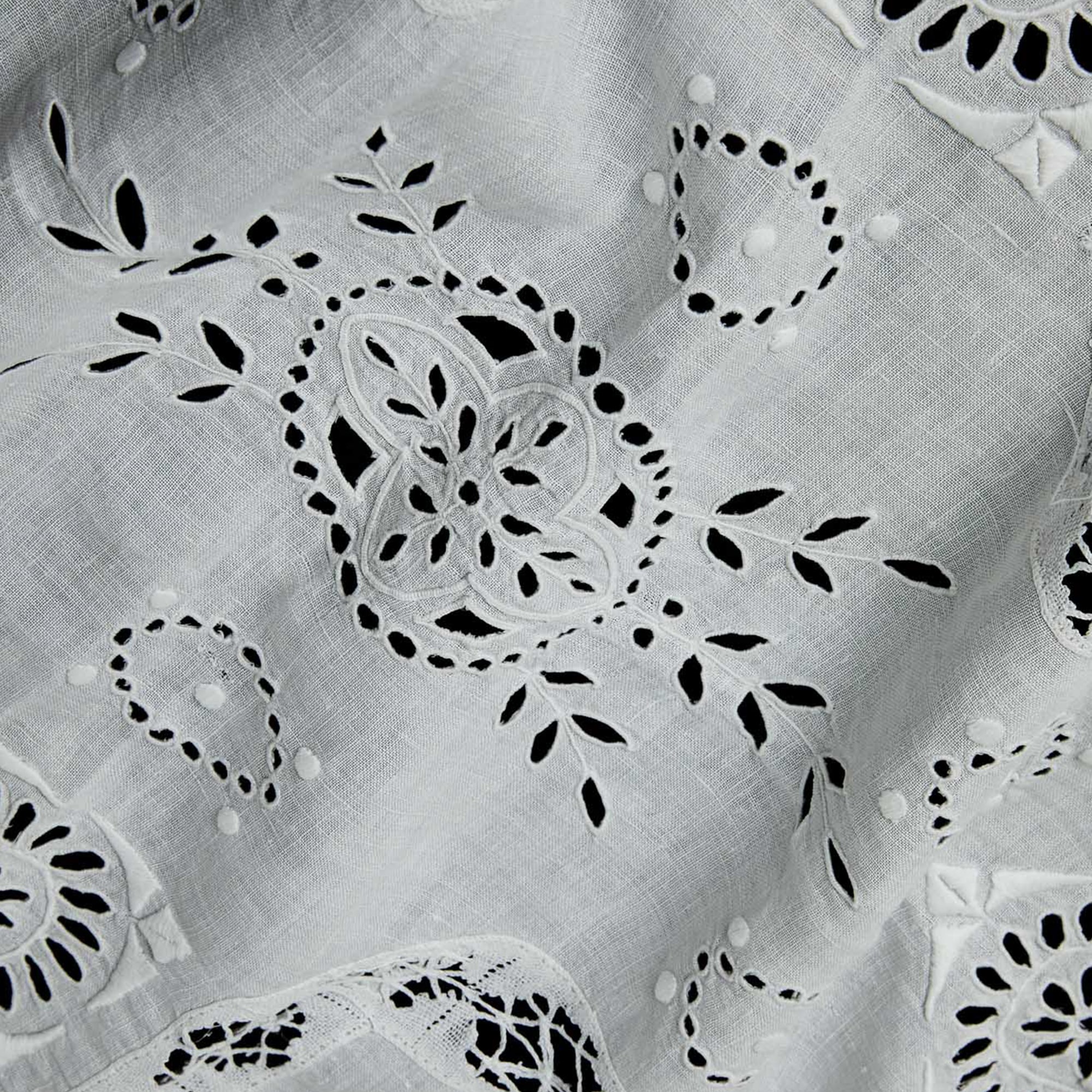 Close-up of openwork embroidery on white linen table runner handmade in Portugal.