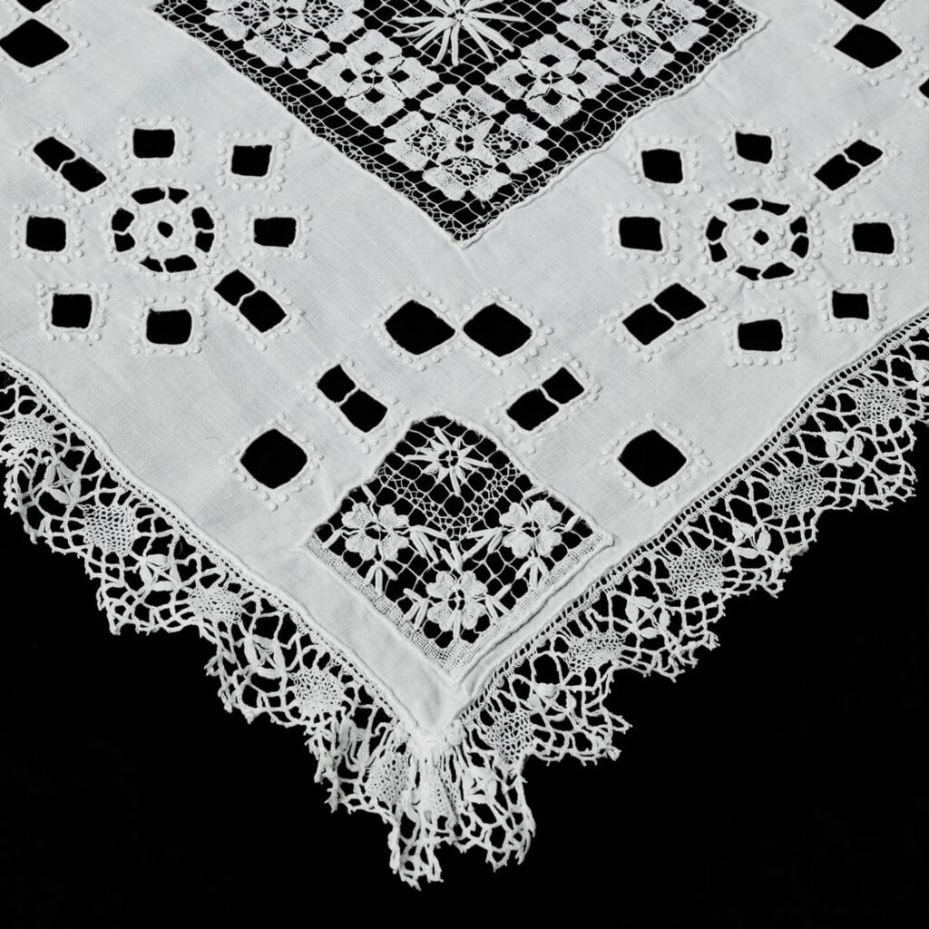 Handmade white linen table runner with bobbin lace and open embroidery detail.