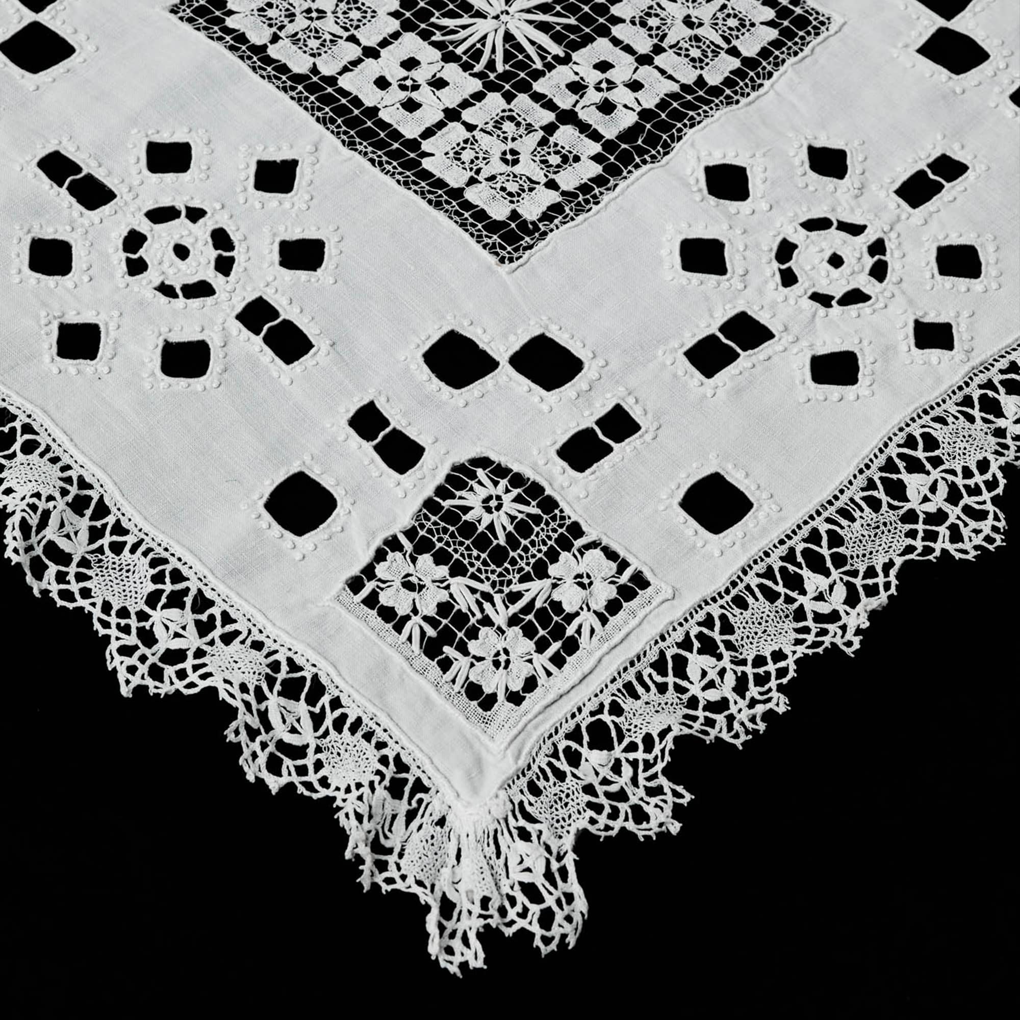 Handmade white linen table runner with bobbin lace and open embroidery detail.