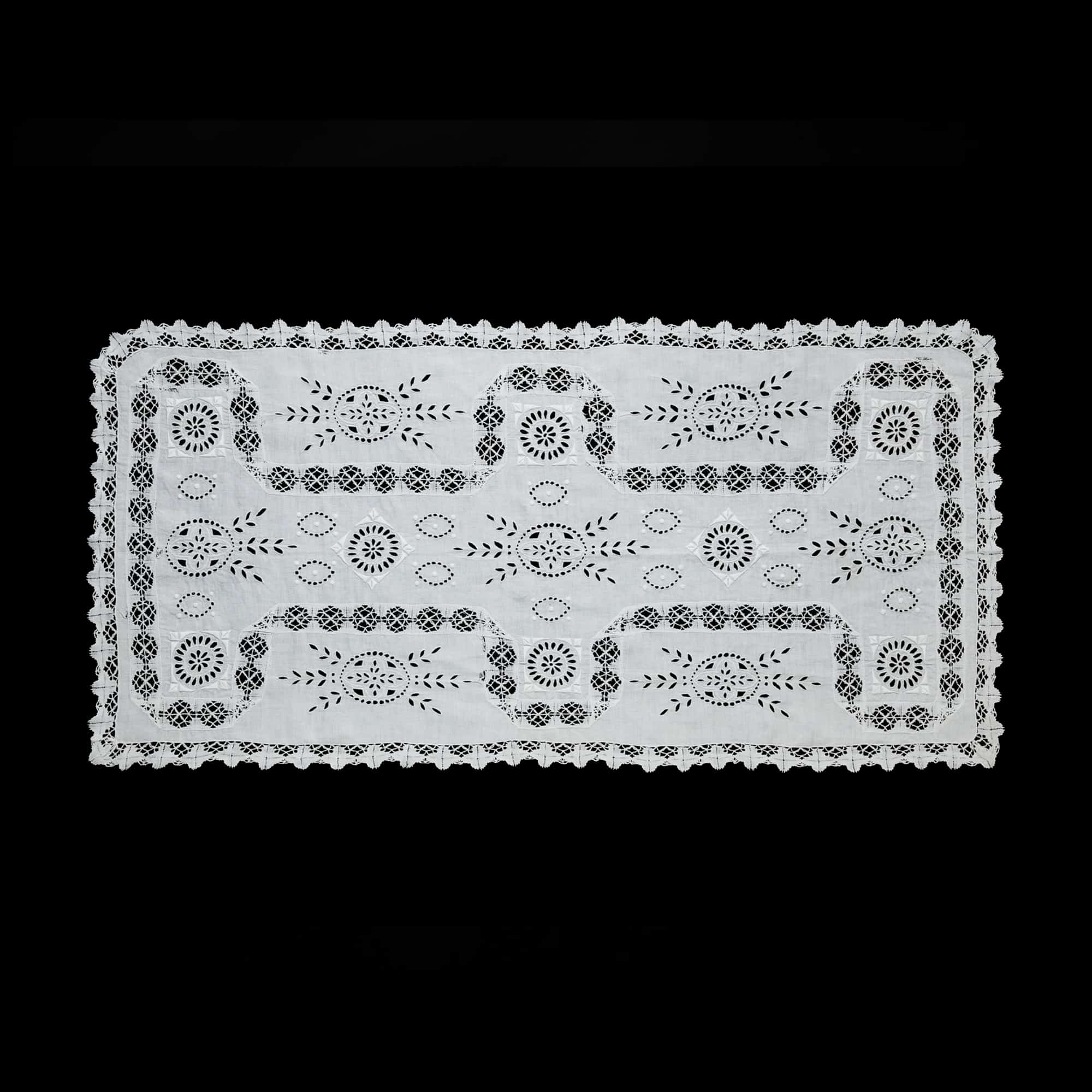 White linen table runner with openwork embroidery, artisan-made in Portugal.